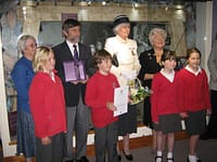 Clive Benney holds the certificate and Roger Radcliffe the crystal in its purple box in front of the Museum